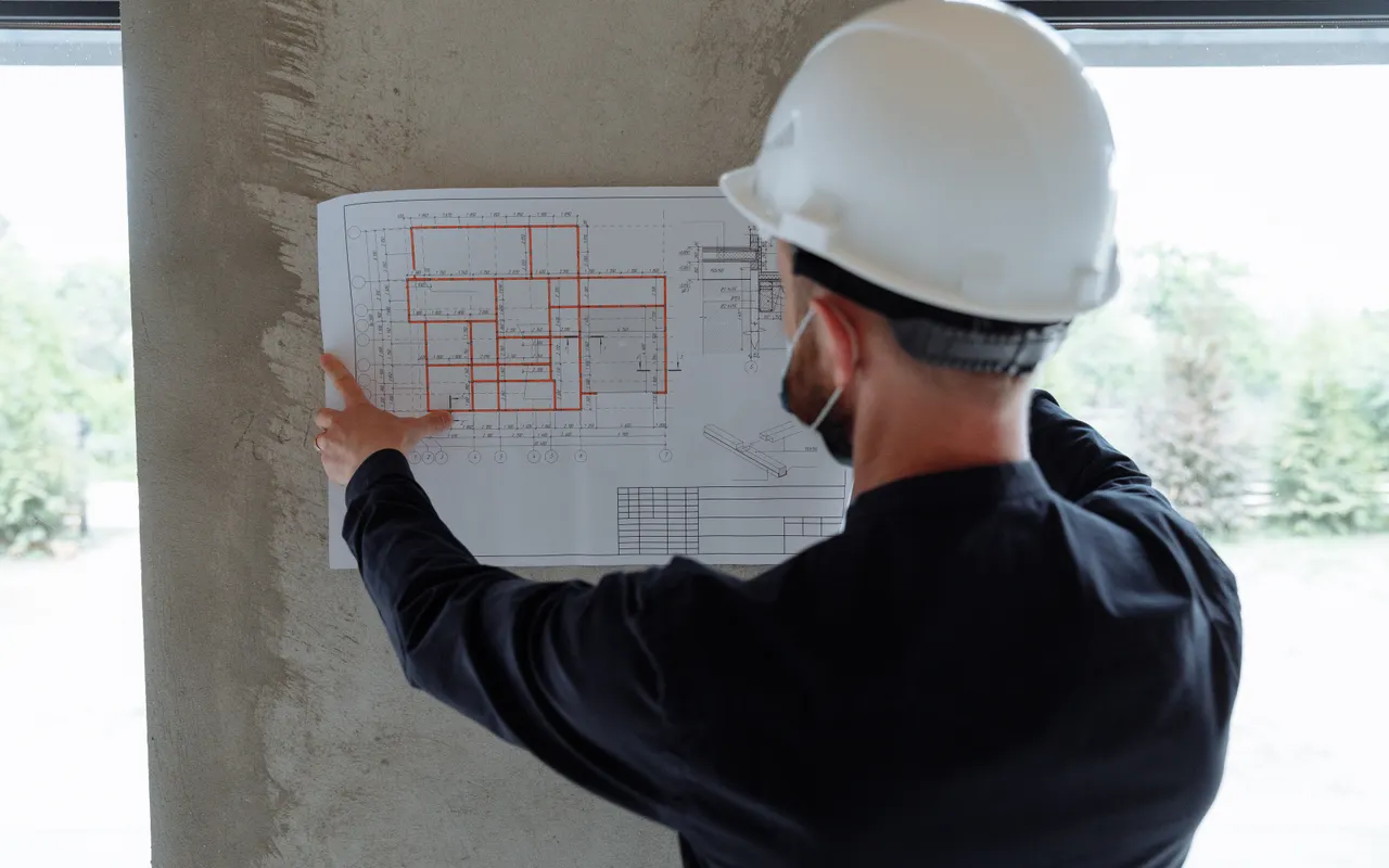 Bouwprofessional bekijkt een tekening met een veiligheidshelm op