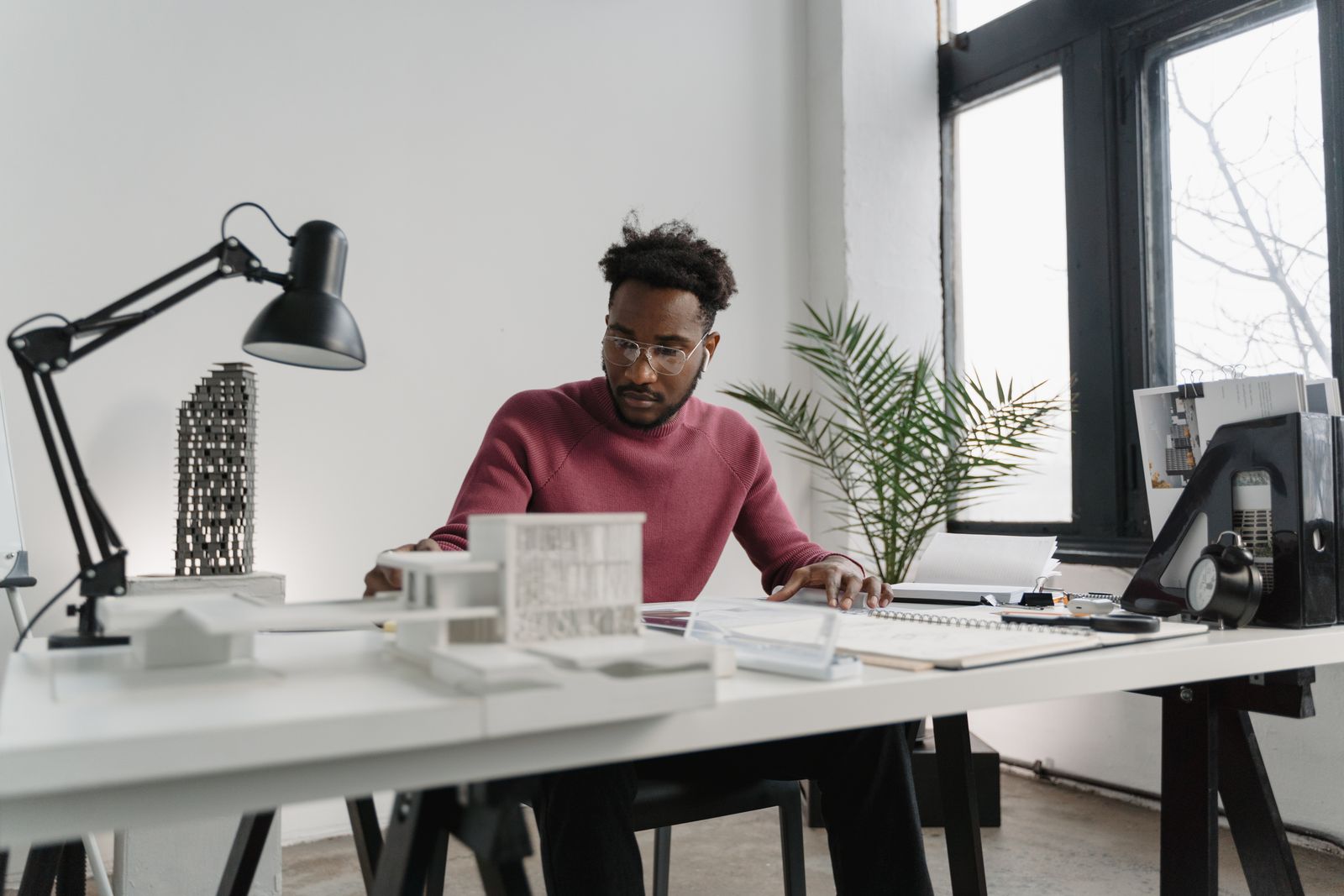 Een professional werkt aan bouwtekeningen en modellen aan zijn bureau