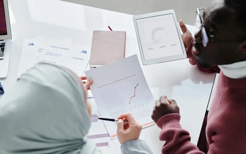 AI-edited stock photograph: colleagues review a budget using documents and a tablet.