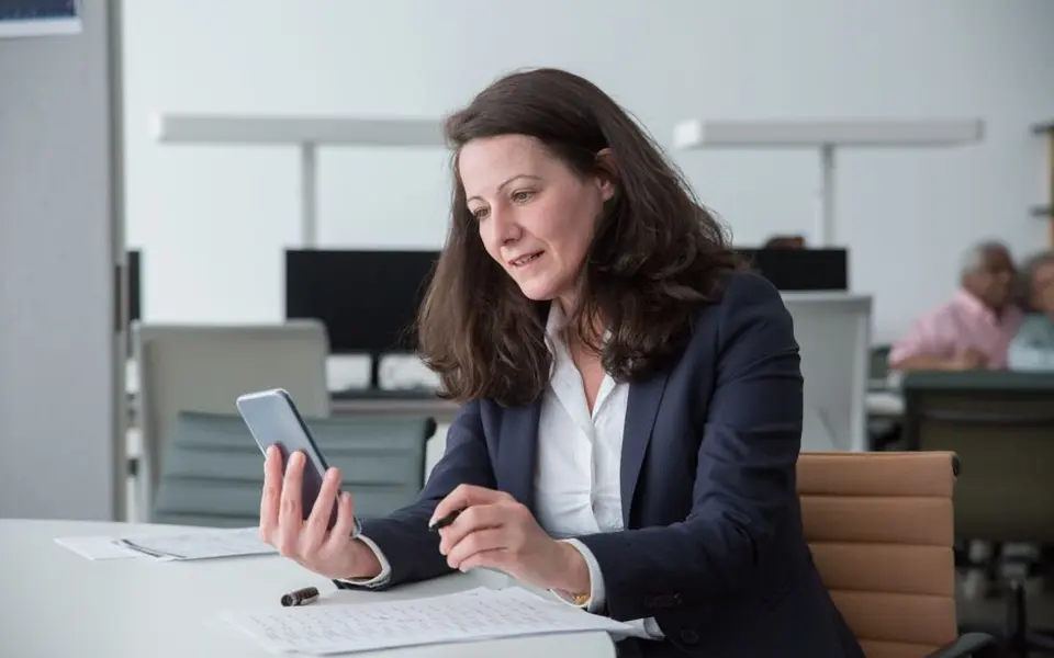 Een medewerker gebruikt haar telefoon op kantoor